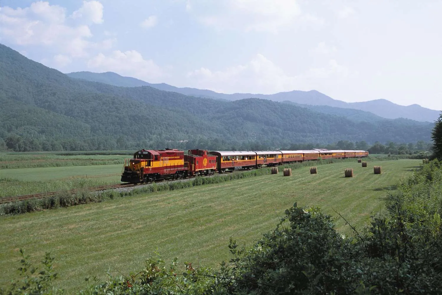 Aerial view of Great Smoky Mountains Railroad train winding through scenic mountain landscape with autumn foliage