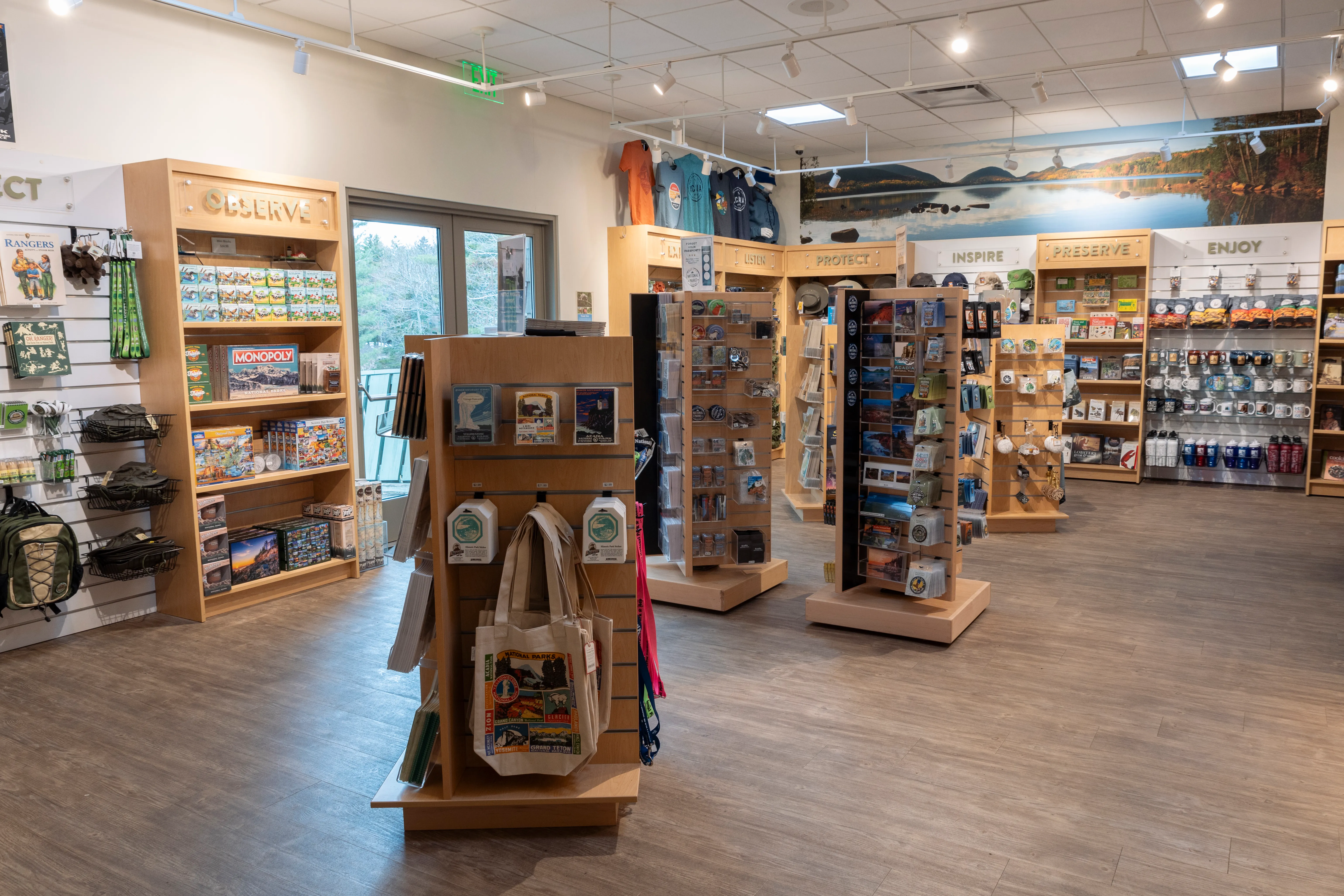 Interior view of Acadia National Park official gift shop with wooden shelves displaying games, clothing, and souvenirs