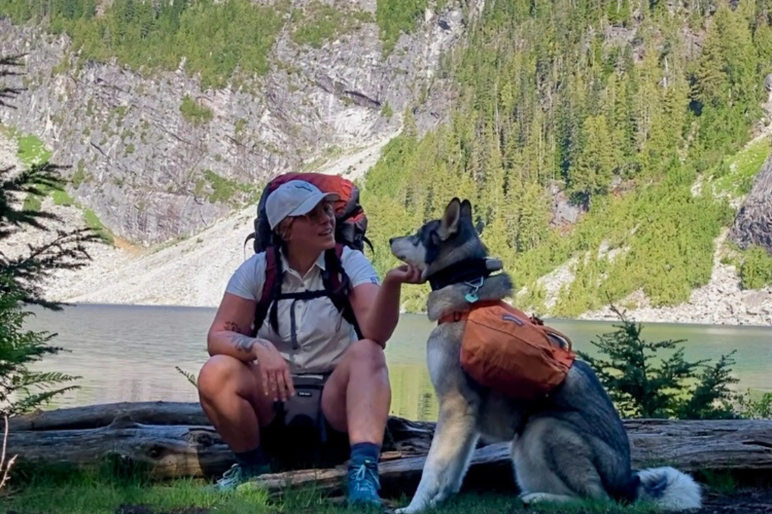 Woman wearing a high-performance moisture wicking hiking shirt while backpacking near a mountain lake, demonstrating real-world trail performance
