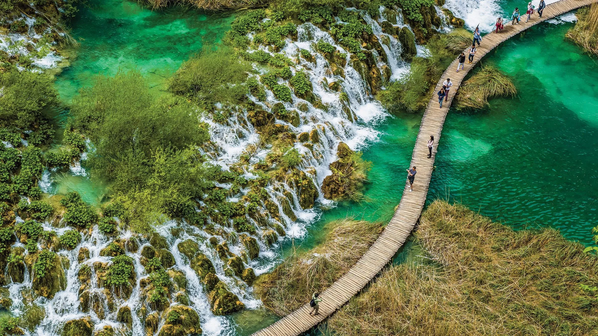 Beautiful mountain hiking trail with crystal clear lake surrounded by dramatic peaks