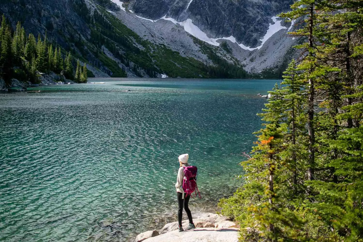 Woman hiking on scenic mountain trail with dramatic mountain peaks in background