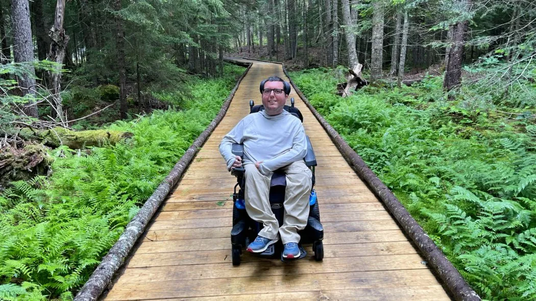 Wheelchair user enjoying panoramic mountain views from accessible overlook trail demonstrating the possibilities of accessible national park adventures