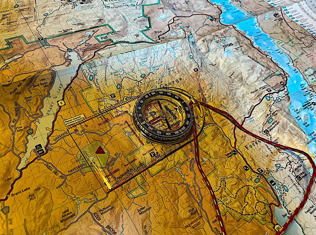 Hiker using compass for navigation on mountain trail