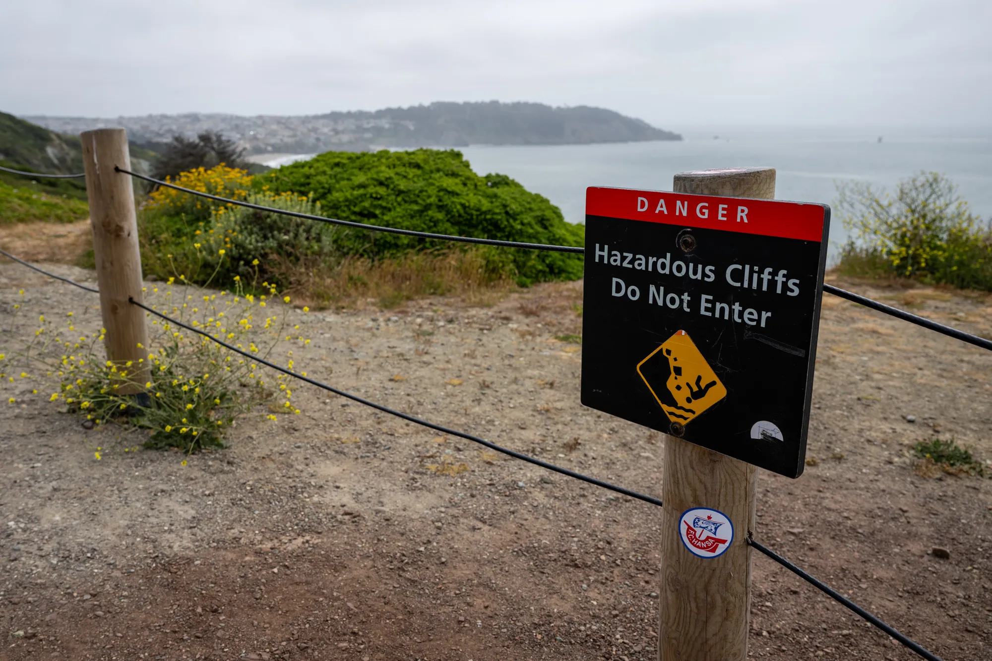 Warning sign about hazardous cliffs along hiking trail