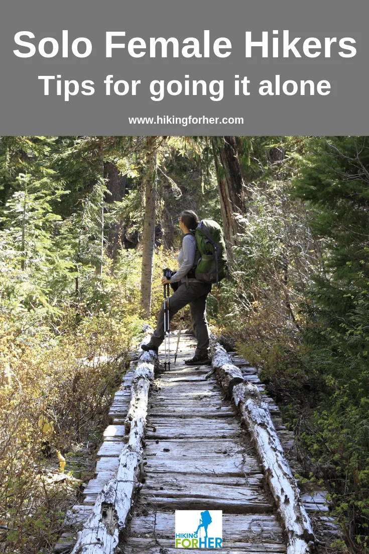 Female solo hiker planning route with map and compass