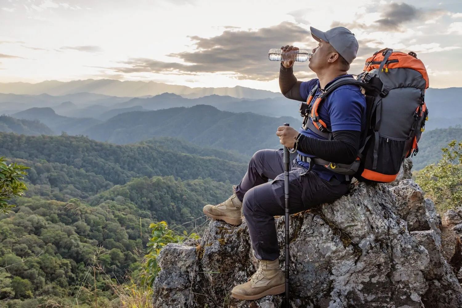 Backpacker drinking water from bottle on mountain trail