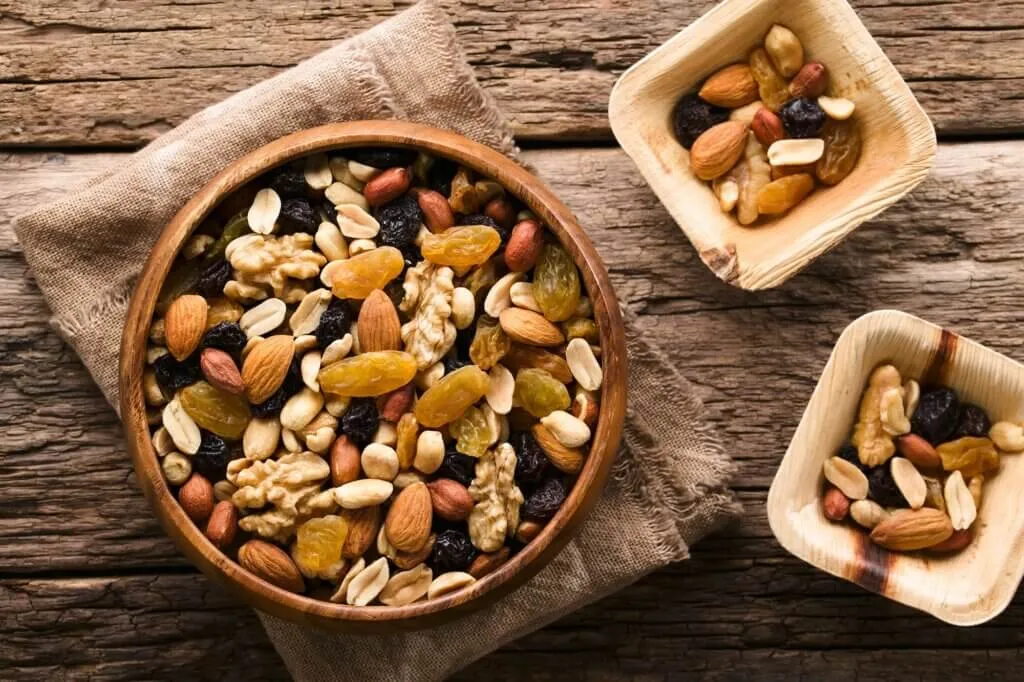 Healthy hiking snacks arranged on a wooden surface with proper food safety containers, demonstrating safe trail snacking practices