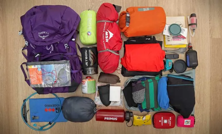 Complete backpacking gear layout showing clothing, boots, and essential equipment