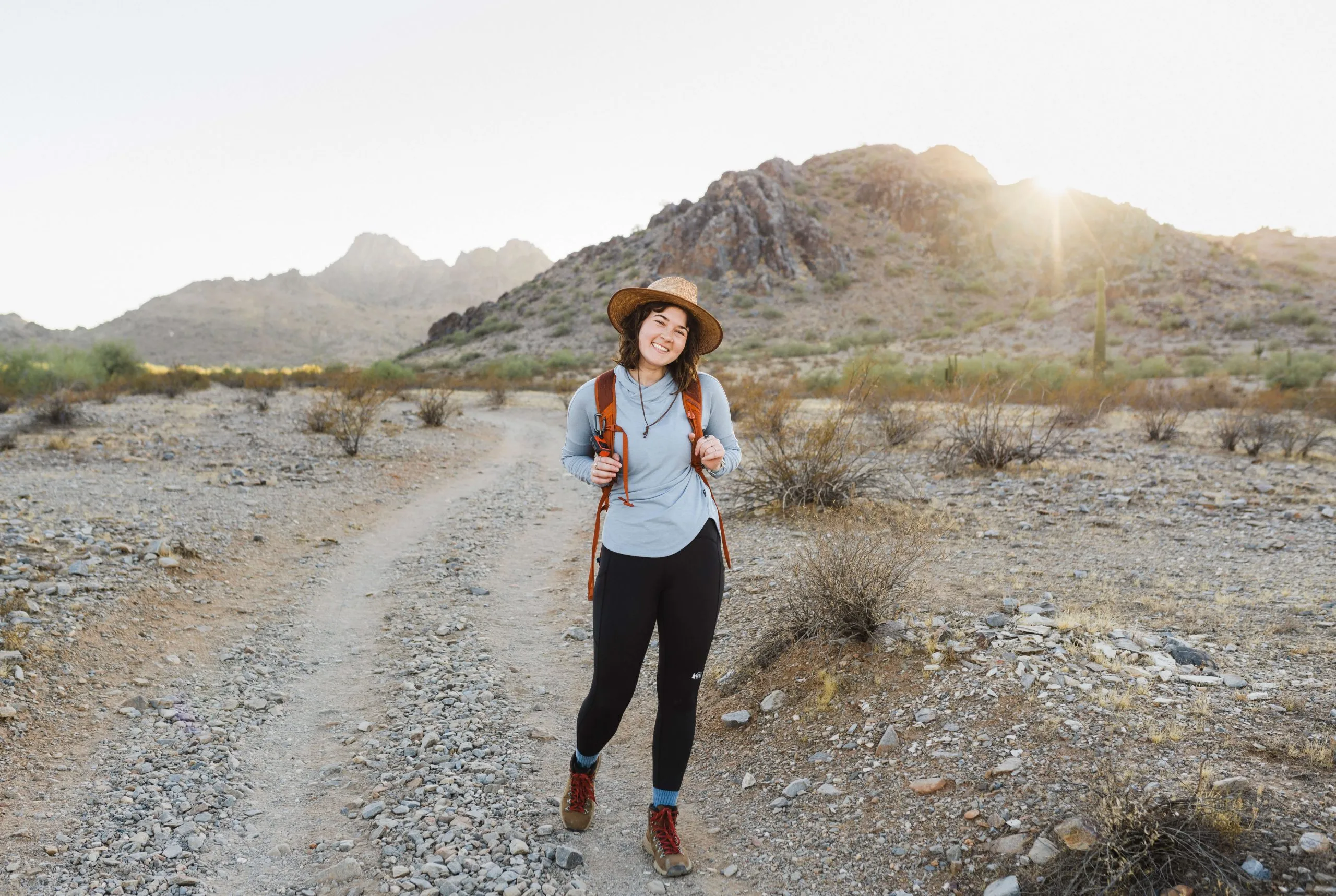 Woman modeling complete hiking outfit with hiking pants, top, and gear