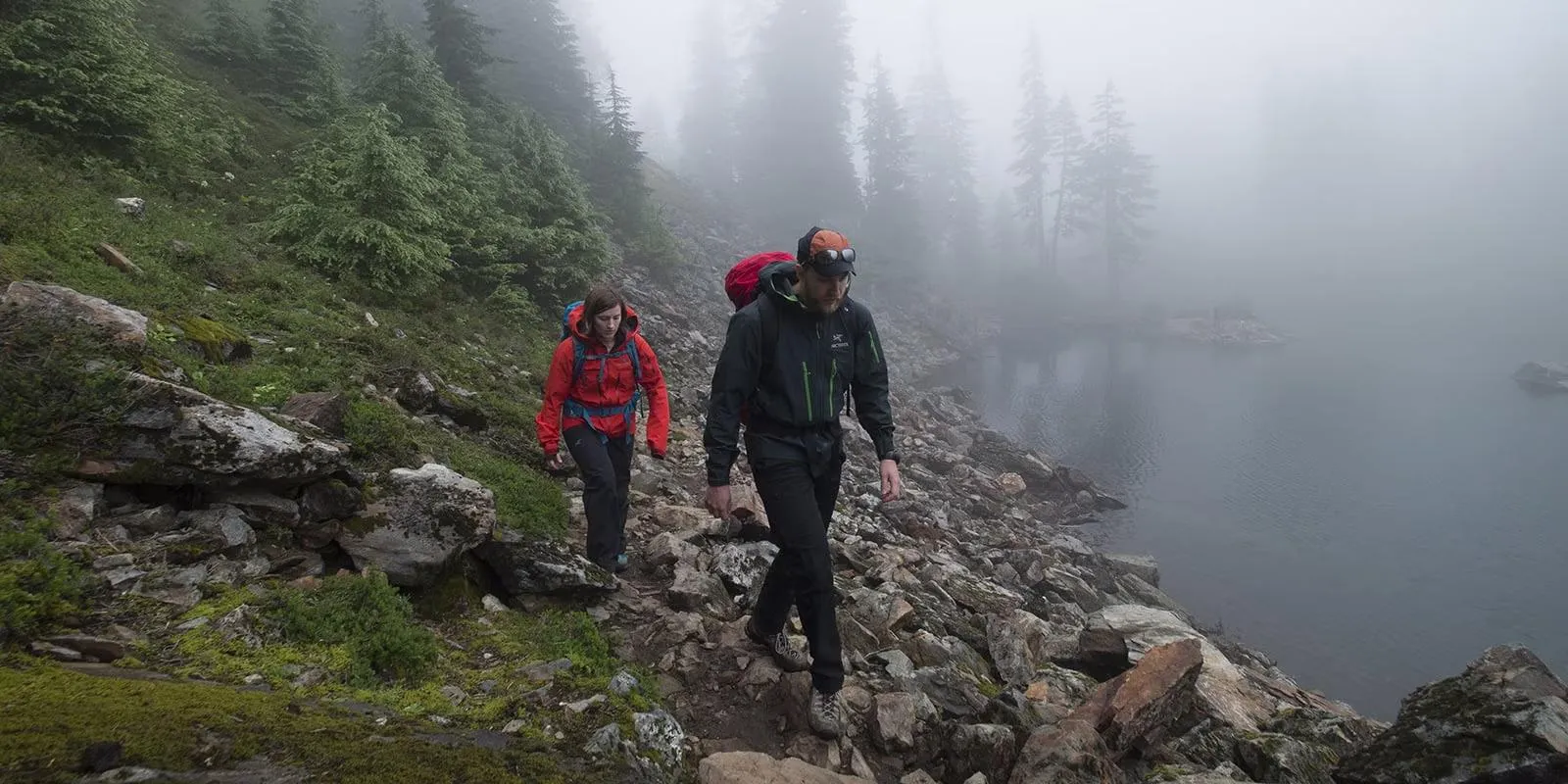 Hiker checking weather conditions on mountain trail with storm clouds approaching