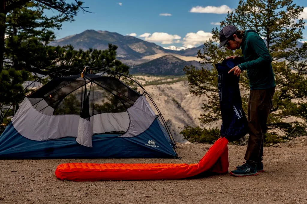 Hiker inflating sleeping pad in outdoor setting