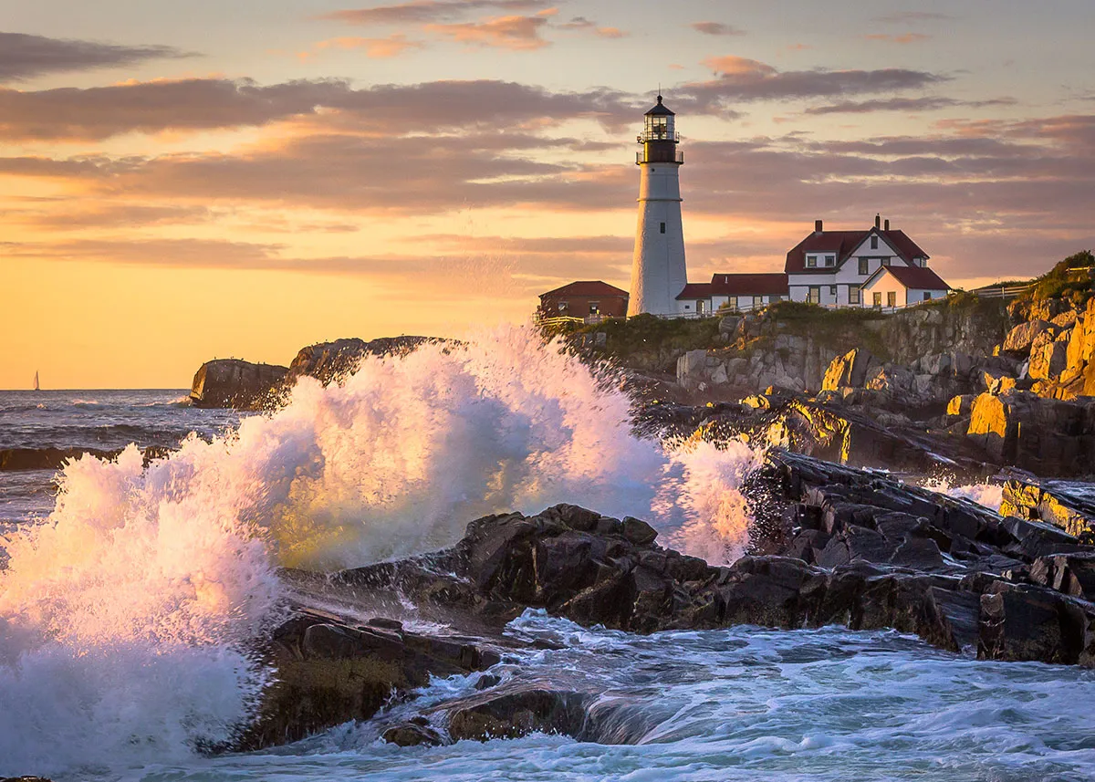 Portland Head Lighthouse perched on rocky Maine coast with waves crashing below