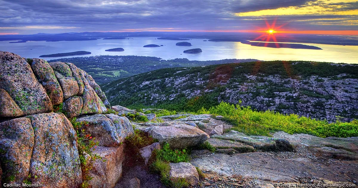 Spectacular sunrise view from Cadillac Mountain summit with golden light illuminating the Maine landscape