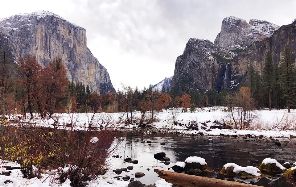 Yosemite Valley covered in winter snow with granite cliffs and frozen Merced River