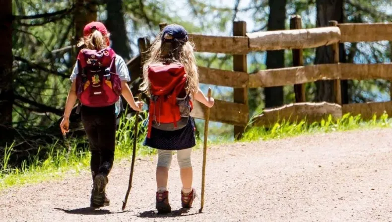 Happy children with hiking gear and muddy smiles after completing a nature trail